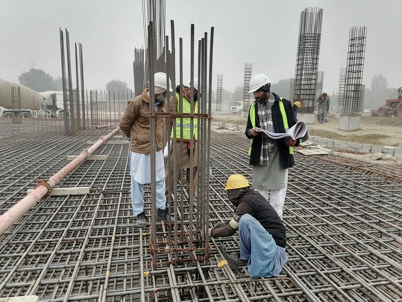 Construction workers and engineers at a site in Bahāwalnagar, Punjab, Pakistan, inspecting metal framework.