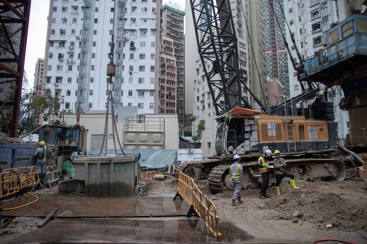 service-02 City construction site with workers, cranes, and high-rise buildings.